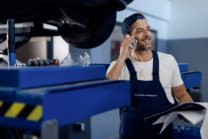 A mechanic talks on the phone with the experts of Hotline Logicat while working at auto repair